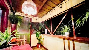 A cozy, rustic room with a wooden ceiling, a red table, and several potted plants. - Downtown Cottage with Private Hot Tub (Eureka Springs)
