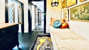 A hallway with a sofa and decorative pillows, a patterned rug, and wall art. - Downtown Cottage with Private Hot Tub (Eureka Springs)