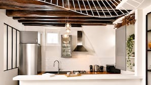 A modern kitchen with a central island, stainless steel appliances, and bar stools. - Spacious & modern property in Le Marais (Paris)