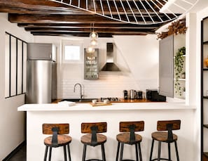 A modern kitchen with a central island, stainless steel appliances, and bar stools.