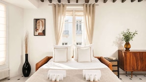 A bedroom with a bed, curtains, a vase, a cabinet, and a painting on the wall. - Spacious & modern property in Le Marais (Paris)