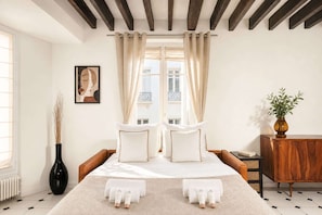 A bedroom with a bed, curtains, a vase, a cabinet, and a painting on the wall.