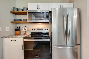 A modern kitchen with stainless steel appliances, including a refrigerator, microwave, and oven.