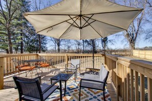 An outdoor deck with a large umbrella, metal chairs, a table, and a patterned rug. - The Leaf Lodge - Walking Distance to MTSU 3Bed/2Ba (Murfreesboro)