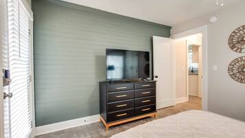 A bedroom with a bed, a dresser, a mirror, and a door leading to a bathroom.