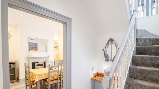 Una escalera que lleva a un rellano con barandilla blanca y suelo de madera.