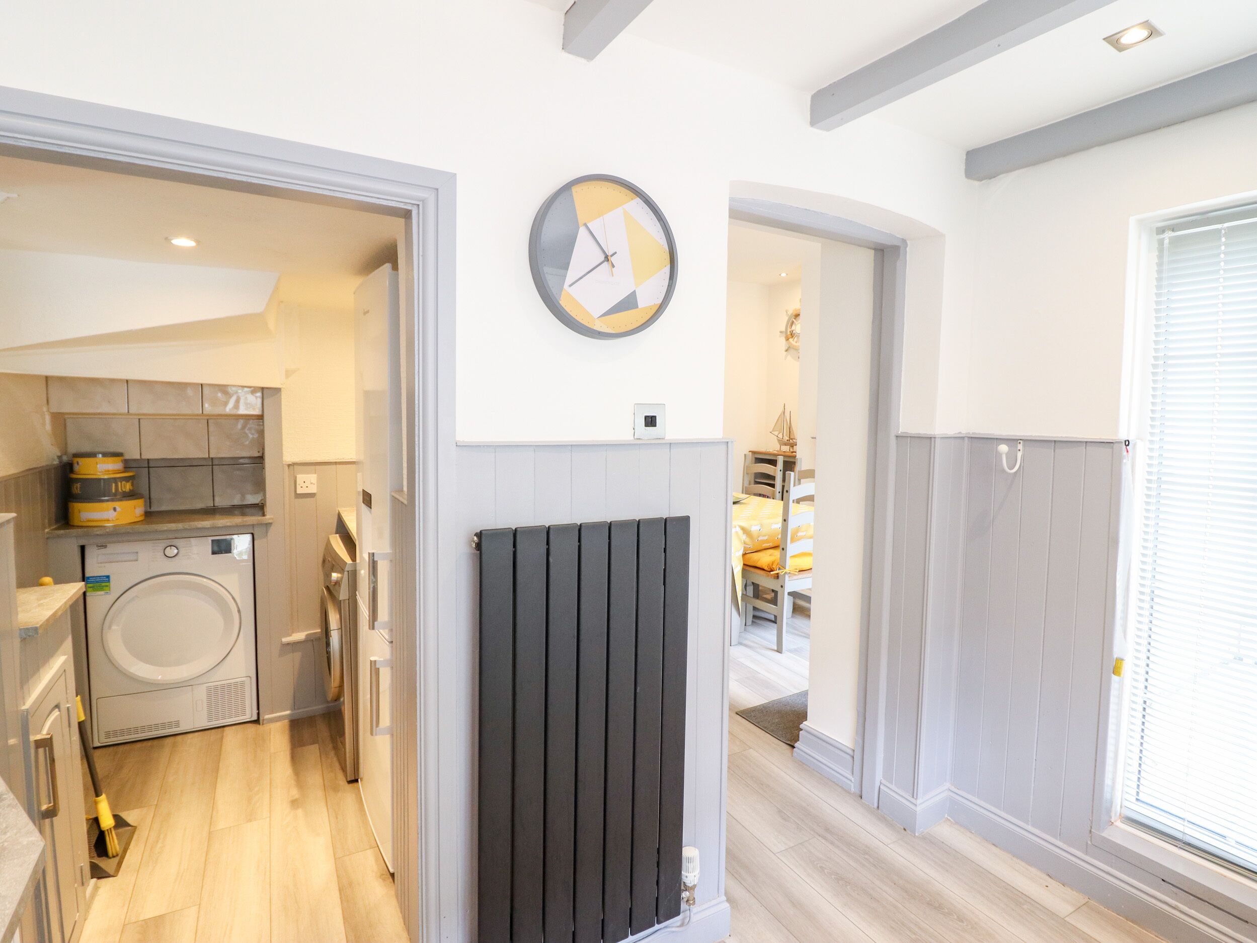 Une cuisine moderne équipée d’un lave-linge encastré, d’un radiateur et d’une horloge murale.