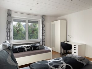 Un dormitorio moderno con cama, escritorio y armario.