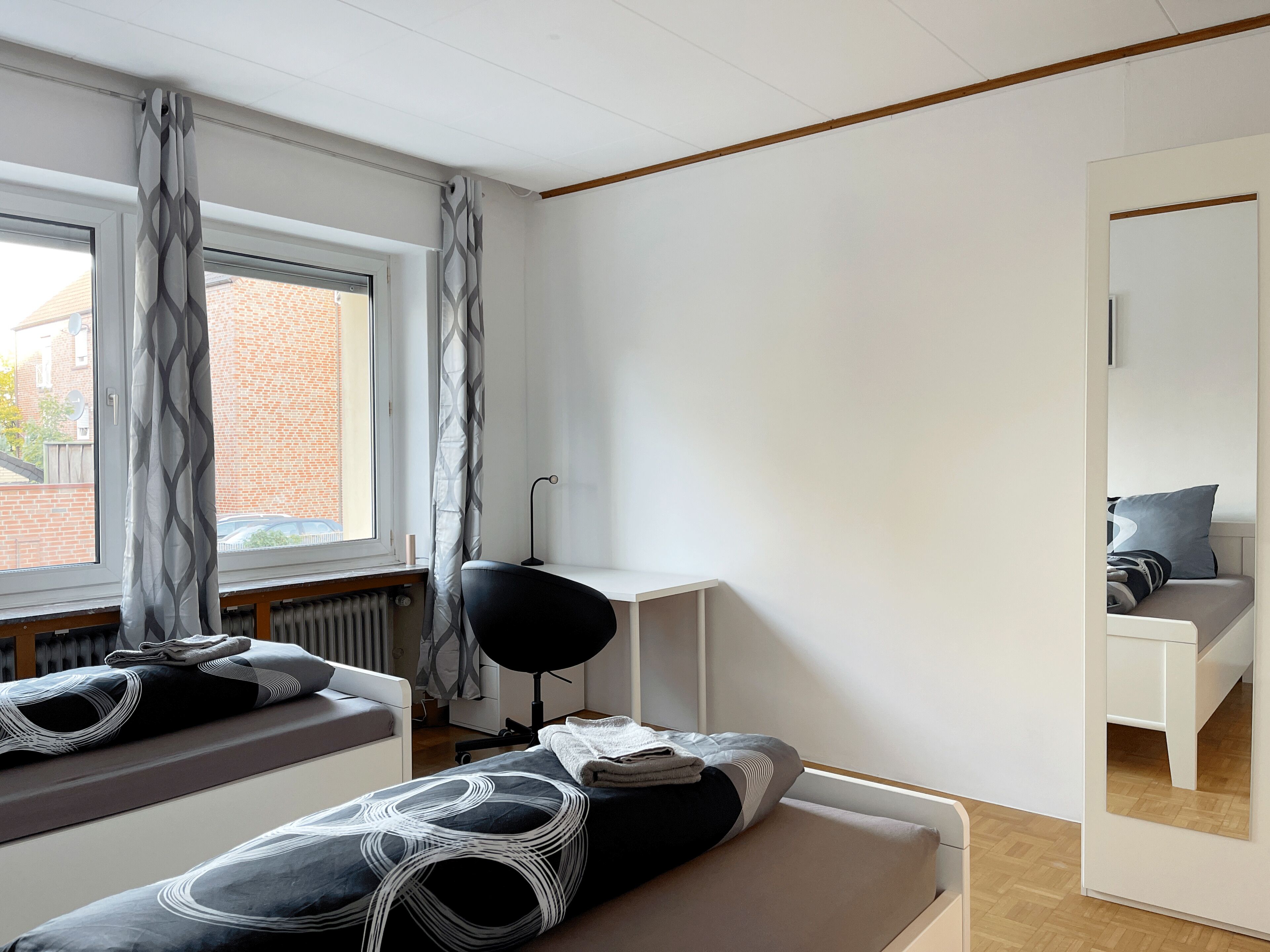 Una camera da letto moderna con un'ampia finestra, una scrivania e un letto con biancheria decorata.
