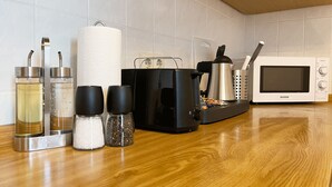 A kitchen with a microwave, a toaster, and various containers on the counter.