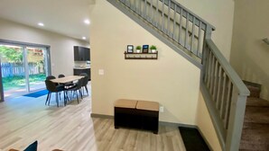 A modern living room with a staircase, a dining area, and a view of the backyard.