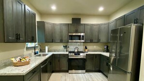 A modern kitchen with dark cabinets, stainless steel appliances, and a granite countertop.