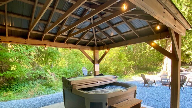 A covered hot tub area with wooden benches and a pergola overhead.