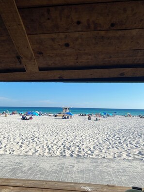 A beach with a lifeguard tower, umbrellas, and people.