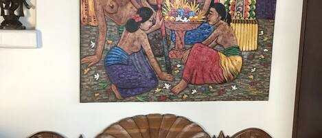 A wall-mounted painting of a traditional scene with figures and a musical instrument.