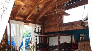 A rustic interior with wicker furniture, a wooden dining table, and a ceiling fan. - The Bali House Experience: Enjoy The Peace (Tucson)
