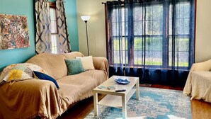 A living room with a beige sofa, a coffee table, and a blue patterned rug.