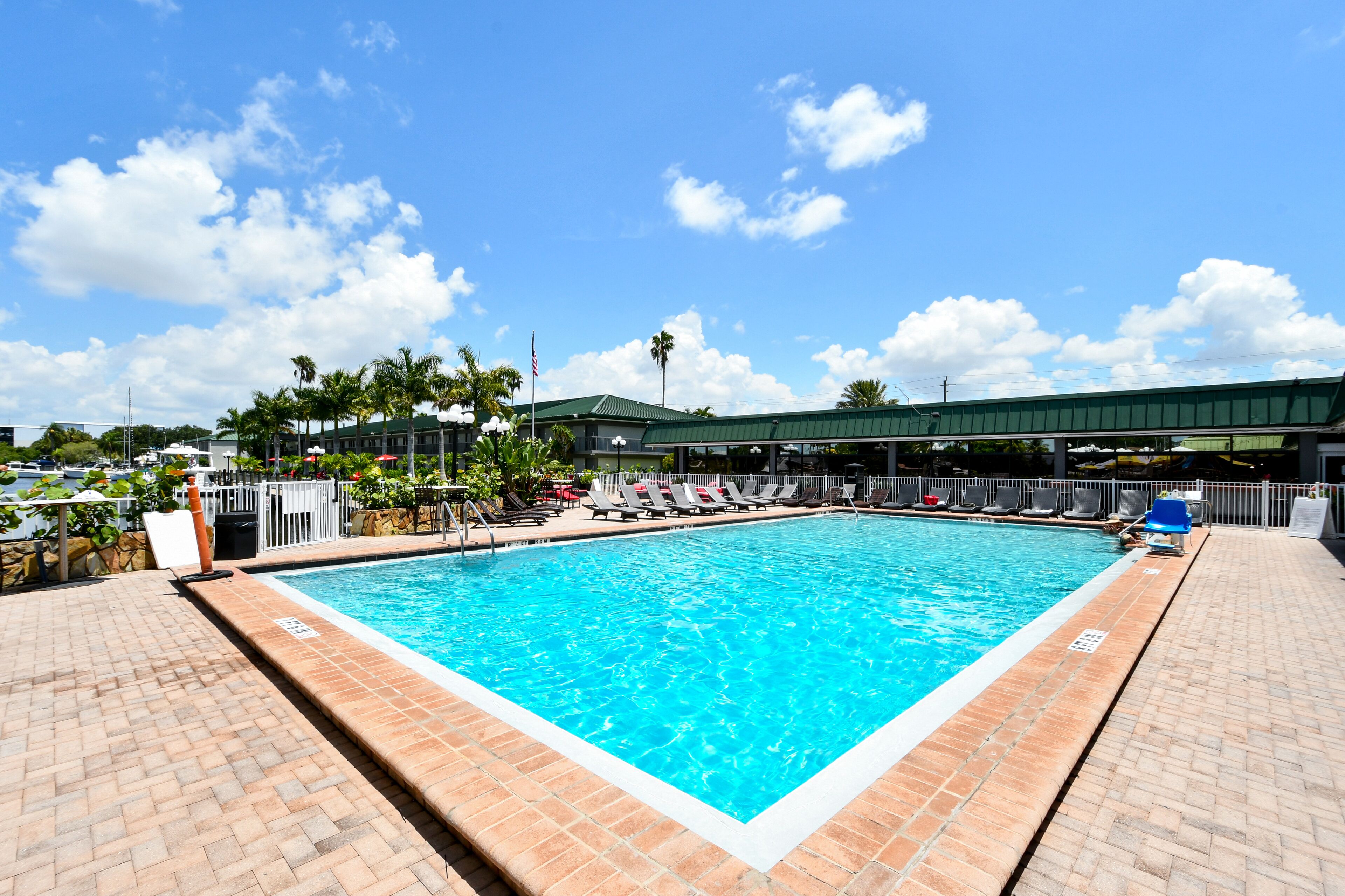 Una piscina rectangular con agua azul cristalina, rodeada por un suelo de baldosas.
