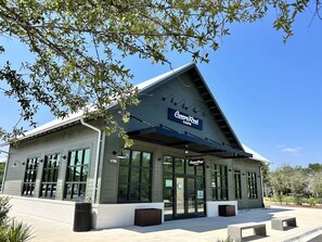 A building with a large glass entrance, a sign reading "Canyon Creek Cafe," and a covered outdoor seating area.