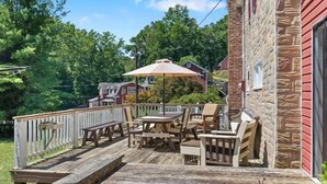 A wooden deck with outdoor furniture, a table, and a bench. - Charming cottage overlooking pond and meadows (Holtwood)