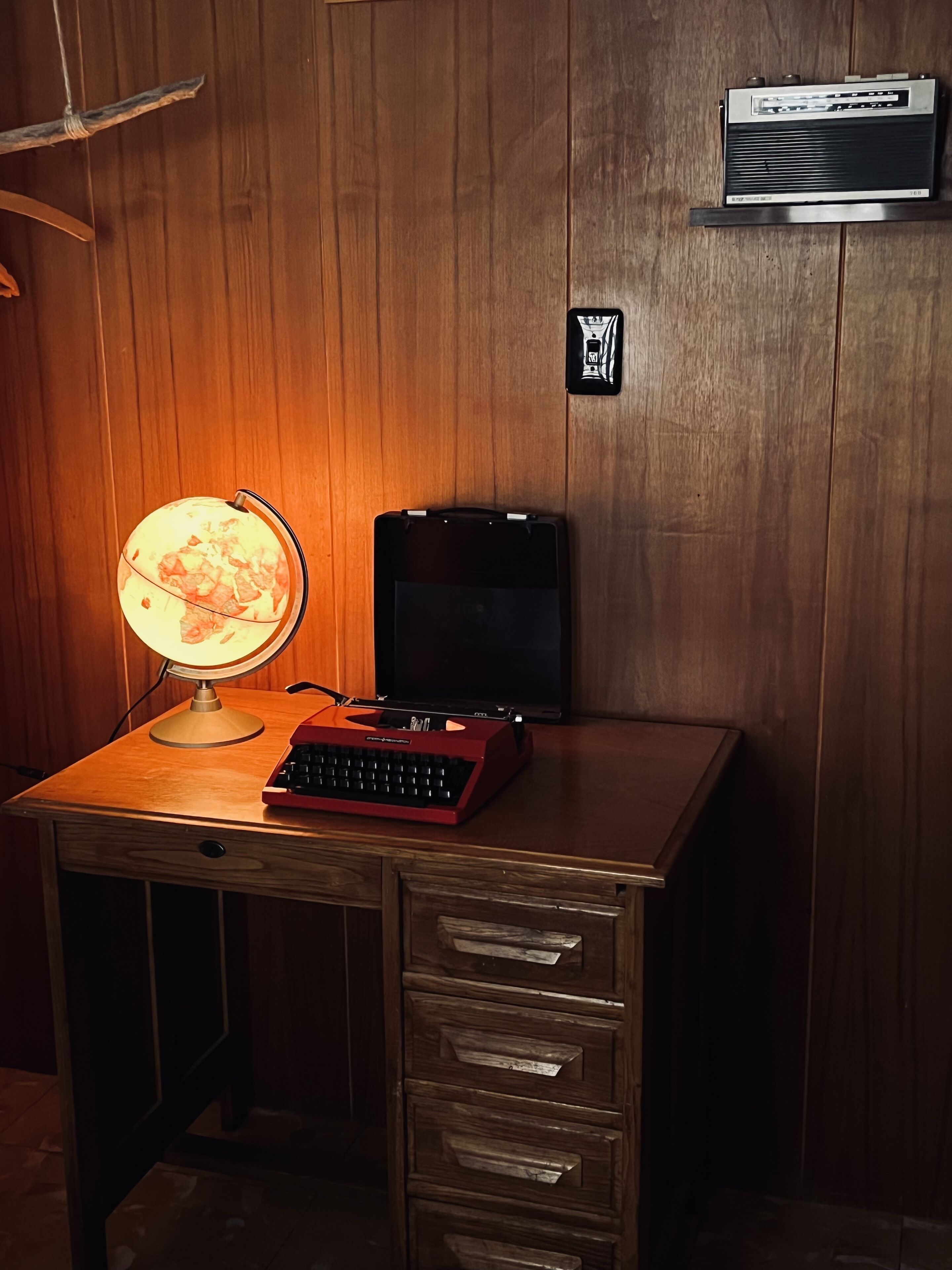A wooden desk with a globe lamp, a typewriter, and a radio.