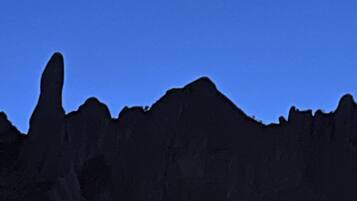 Silueta de una cordillera contra un cielo nocturno con luna visible.