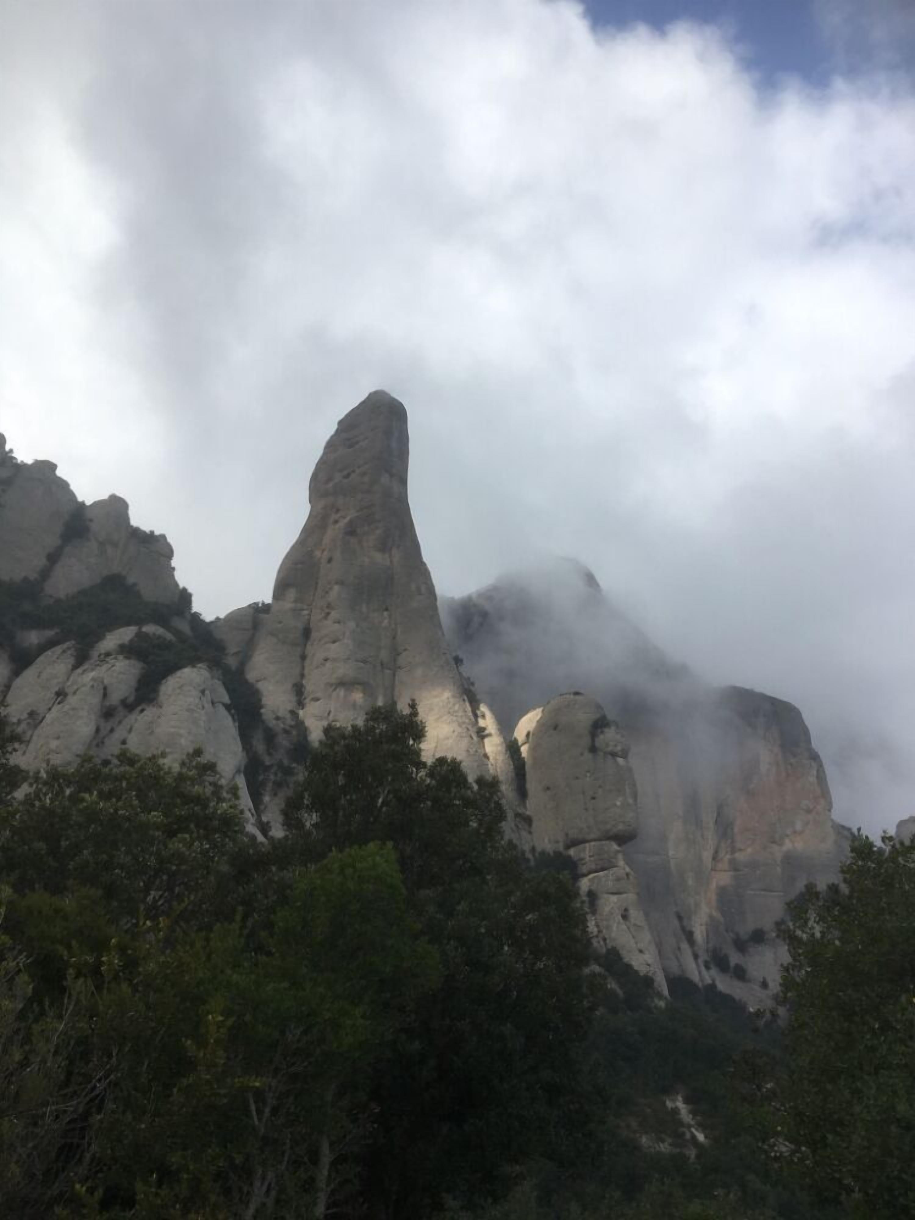 Un paysage montagneux accidenté, caractérisé par d’imposantes formations rocheuses et une forêt dense à ses pieds.