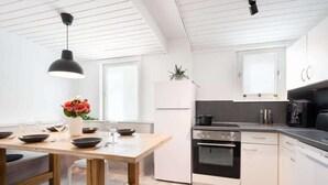 Una cocina moderna con armarios blancos, una mesa de comedor de madera y una lámpara colgante negra.