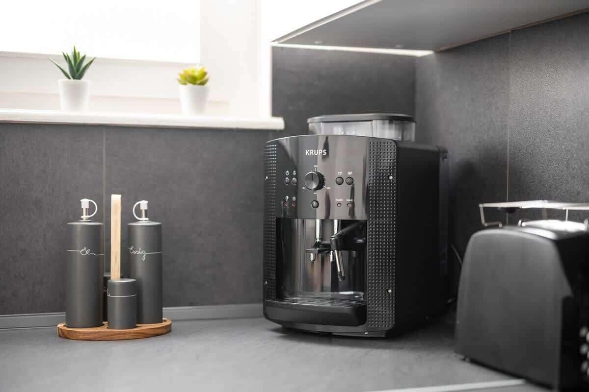 Eine moderne Küche mit einer Kaffeemaschine, zwei Kaffeeautomaten und einem kleinen Blumentopf auf der Fensterbank.