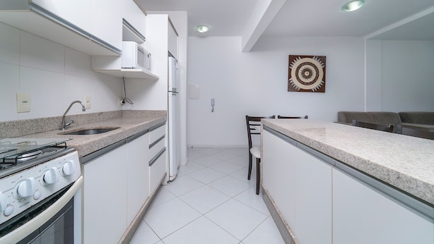 Una cocina moderna con armarios blancos, encimera de granito, estufa integrada y microondas.