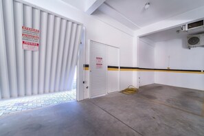Eine saubere, leere Tiefgarage mit einer weißen Tür, einem gelb-schwarz gestreiften Boden und einem Schild, das Fußgängerzugang anzeigt.
