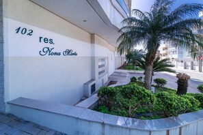 Ein Gebäude mit einem Schild, auf dem '102 res. Nona Marta' steht, und ein kleiner Garten mit einer Palme.