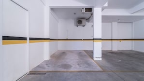 Un estacionamiento con paredes blancas, franjas amarillas y negras, y pisos de concreto.