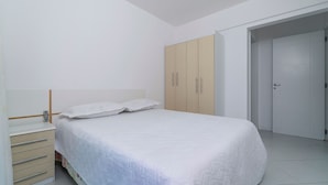 Un dormitorio con cama, armario, mesita de noche y puerta.