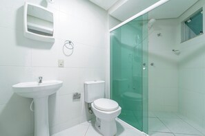 A modern bathroom with a glass-enclosed shower, a white sink, and a toilet.