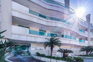 A multi-story building with balconies, a sign indicating '102 res. Nona Marta', and a palm tree in the foreground.