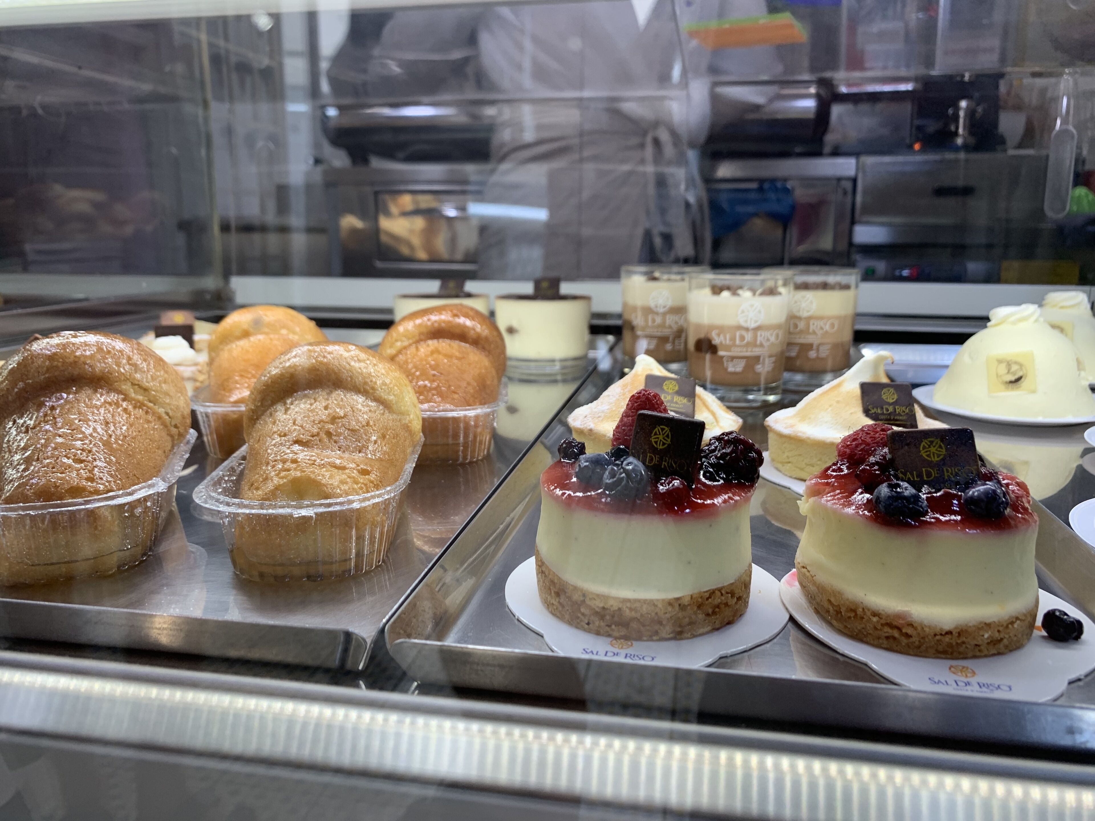 A display case with various desserts, including cakes and pastries, in a bakery or cafe setting.