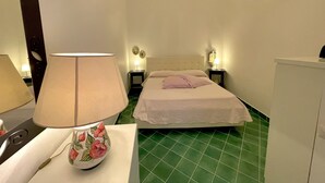A hotel room with a bed, a nightstand with a lamp, a mirror, and a dresser.