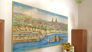 A colorful mosaic of a coastal town with buildings, a pier, and boats.