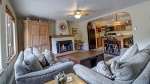 A living room with a fireplace, sofa, coffee table, and a view into the kitchen. - Rare Gem, Spacious Condo, Outstanding Location A6 (Copper Mountain)