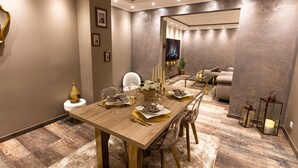 A dining area with a wooden table set for four, surrounded by chairs.