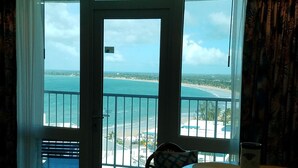Une chambre avec vue sur la plage et l’océan, accessible par une porte vitrée.