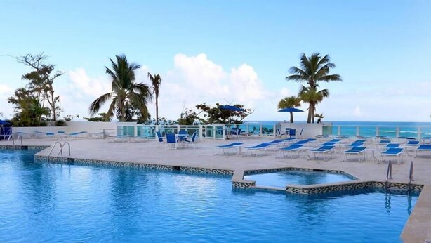 A pool area with lounge chairs and palm trees, overlooking the ocean. - Beach HotelCndo 1562 (Carolina)