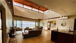 Een ruime woonkamer met een groot raam met uitzicht op een prachtig landschap, een gezellige zithoek met een open haard, en een moderne keuken met een groot eiland.