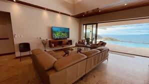 Een moderne woonkamer met een groot raam dat uitkijkt op een schilderachtig uitzicht over de oceaan.