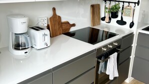 Una cocina moderna con armarios blancos, una cafetera Bosch, un tostador, una tabla de cortar de madera y un colgador para utensilios.