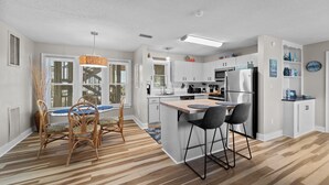 Een moderne keuken met witte kasten, een centraal eiland en barkrukken.