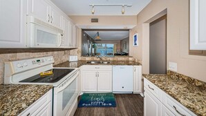 A kitchen with white cabinets, a microwave, a stove, and a dishwasher. - Waterfront 2BR/2BA condo with pool, hot tub, balcony, and Wi-Fi. (St. Petersburg)