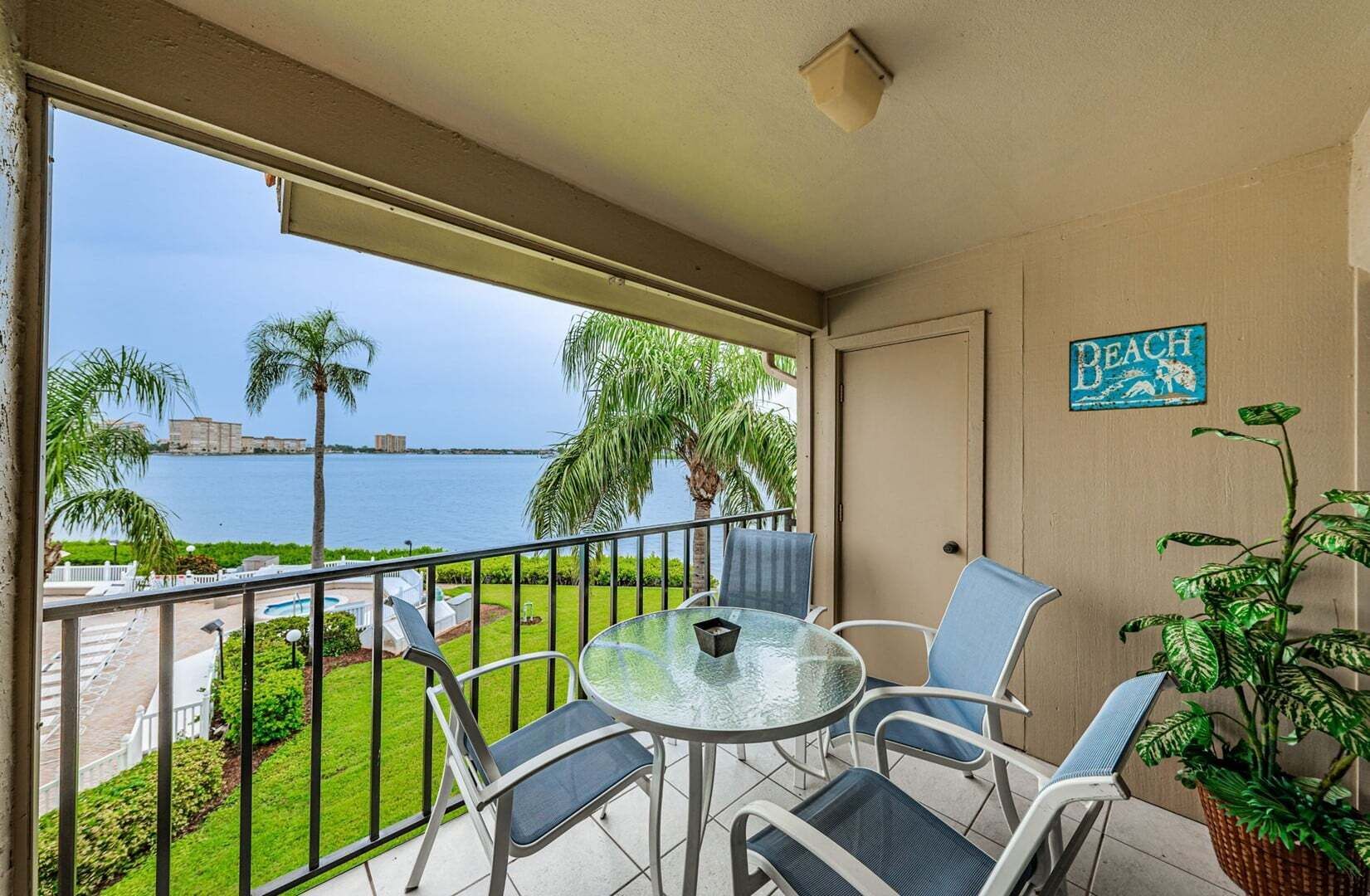 Ein Balkon mit Glastisch und Stühlen, Blick aufs Meer und ein Schild mit der Aufschrift 'BEACH'.