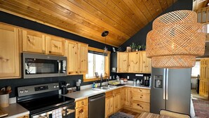 Eine moderne Küche mit Holzausstattung, Edelstahlgeräten und einer großen, gewebten Leuchte.